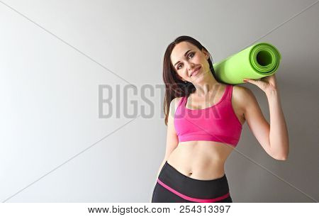 Attractive Woman Wearing Pink Sportswear Holding Green Yoga Or Fitness Mat After Working Out At Home
