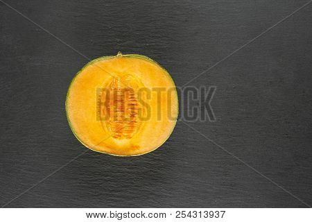 One Half Of Fresh Melon Cantaloupe Variety Flatlay On Grey Stone