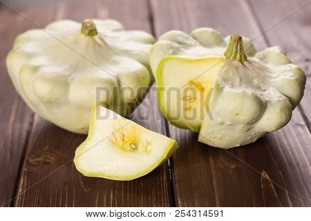 Group Of Two Whole One Slice Of Summer White Pattypan Squash On Brown Wood