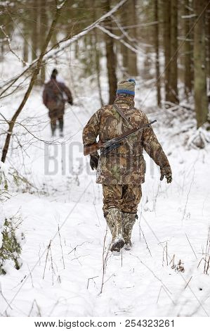 Group Of Hunters In Winter Forest With Carbines And Shotgun
