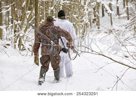 Group Of Hunters In Winter Forest With Carbines And Shotgun