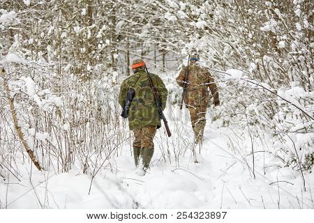 Group Of Hunters In Winter Forest With Carbines And Shotgun