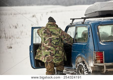 Hunter In Camouflage With With Hunting Car In Winter Forest