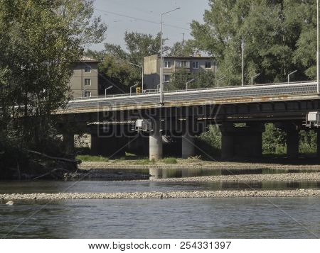 The Bridge Over The Ulba River In Ust-kamenogorsk (kazakhstan). Bridge Over The River And Houses. Fo