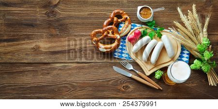 Bavarian sausages with pretzels, sweet mustard and beer on rustic wooden table. Oktoberfest menu