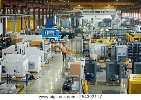 High Angle Full Length Portrait Of Bearded Businessman Wearing Hardhat Walking Across Production Wor