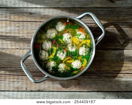 Steel Pan With Turkey Meat Meatballs Soup On Wooden Rustic Table, Hard Sunlight, Hard Shadows, Top V