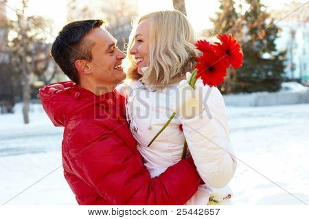 Foto des glücklichen Menschen umarmen hübsche Frau mit Herberas im freien im winter