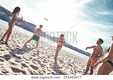 Time With Friends. Group Of Young People Playing Freesby On The Beach