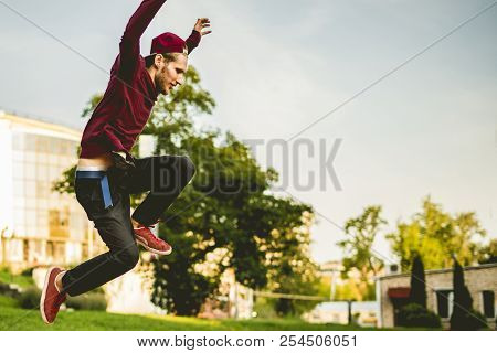 Young Man Freerun In The Summer City Public Park Running, Jumping And Flying, Parkour Concept