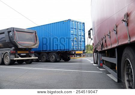 Three Different Type And Color Trucks In The Parking Lot. Tripper, Container Truck And Truck With Ta