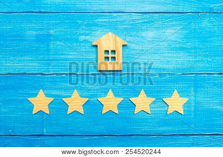 Wooden House And Five Stars On A Gray Background. Rating Of Houses And Private Property. Buying And 