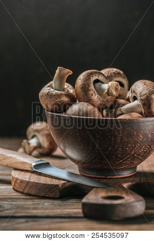 Ripe Cremini Mushrooms In Bowl On Wooden Table Isolated On Black