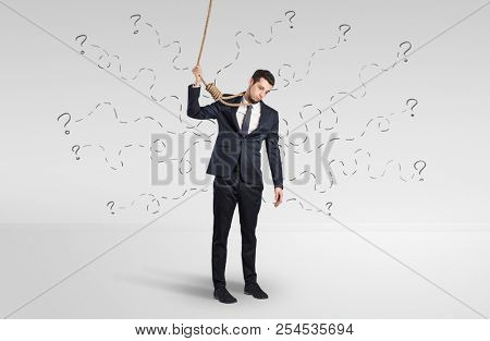 Hopeless young businessman trying to suicide with question signs concept
