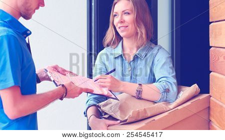 Smiling delivery man in blue uniform delivering parcel box to recipient - courier service concept. Smiling delivery man in blue uniform