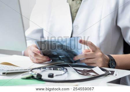 Female Physician At Modern Medical Doctor Office. Woman Examining X-ray At Workplace In Front Of A D