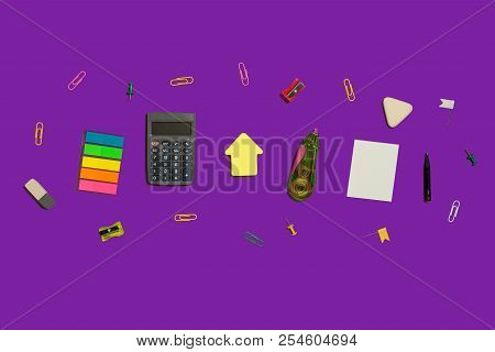 Multiple School And Office Suplies And Gadgets Lying Diagonally On A Purple Background. Free Space F