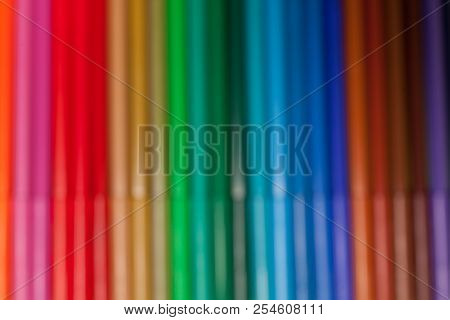 Blurred Photo Of A Row Of Various Bright Multicolored Felt Pens Lying On A Green Surface. Concept Of