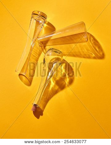 A transparent glass flasks empty lie on a yellow paper background with soft shadows, place for text. Top view. The Chemistry Lab. Various glass chemistry lab equipment. Science and medical background.