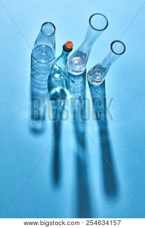 Various glass chemistry lab equipment empty with shadows and reflection on the surface on a light blue background, place for text. The Chemistry Lab.