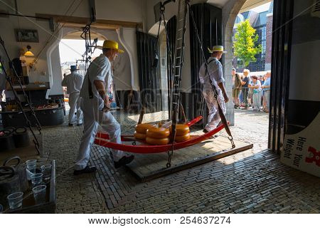 Alkmaar, Netherlands - July 20, 2018: Cheese carriers putting the cheeses on the scale to be weighted in the Waag before being sold on the market 