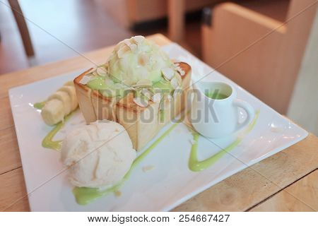 Bread Toast With Vanilla Ice Cream And Pandan Custard,banana And Almond Slice In A White Plate On Wo