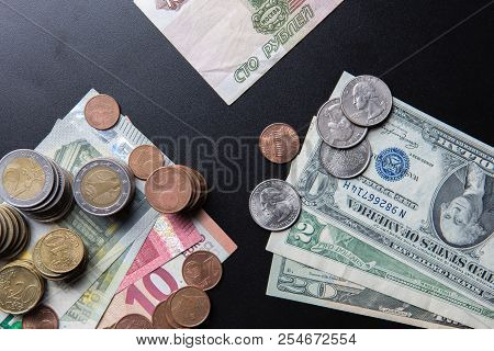 Euros And Usa Dollars Banknotes And Coins With Russian Hundred Rubles Banknote On Black Background. 