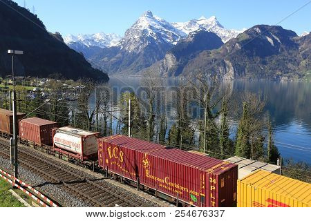Sisikon, Switzerland - April 17, 2018. Freight Train Riding On The Railway Along The Lake Lucerne Ne
