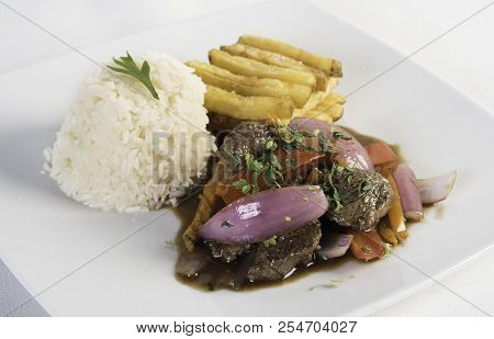 Peruvian Food Lomo Saltado :a Salted Beef With Tomatoes, Onion, Fried Potatoes And Rice. On A White 