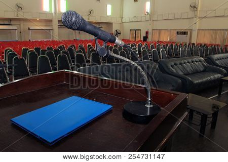 The Microphone Is Located On Podium Stand At The Center Of The Room Is Covered With A Red Carpet Wit