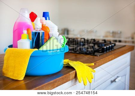 Basket With Cleaning Items On Blurry Background White Citchen. Cleaning Concept.