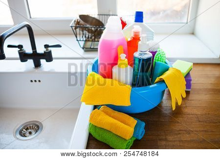 Basket With Cleaning Items On Blurry Background White Citchen. Cleaning Concept.
