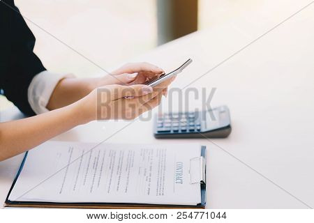 Businesswoman Working With A Mobile Phone Above The Contract And Calculator. Business And Partnershi