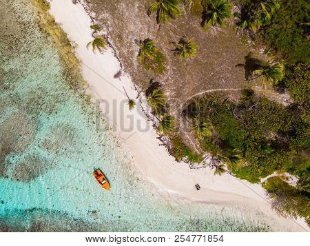 Aerial drone view of Petit Tabac tropical island, turquoise Caribbean sea of Tobago cays, and a family with kids in St Vincent and Grenadines