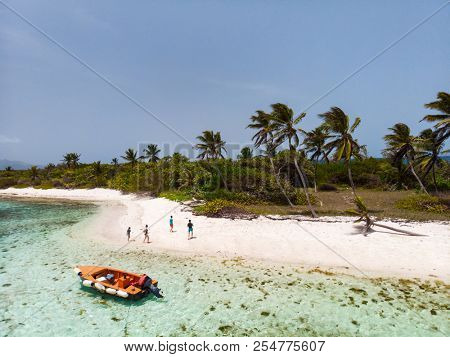 Aerial drone view of Petit Tabac tropical island, turquoise Caribbean sea of Tobago cays, and a family with kids in St Vincent and Grenadines
