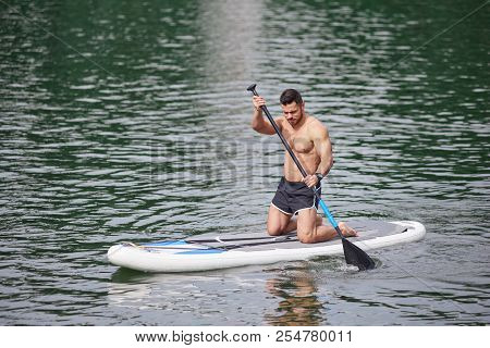 Sporty Man Keeping Oar, Training His Supboarding Skills.