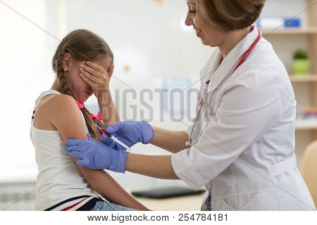 Doctor Pediatrician Holding Syringe With Injection Vaccination. Girl Teenager Is Afraid.