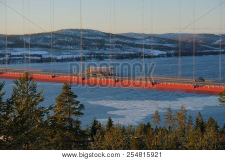 View At Hoga Kusten Bridge In Winter In Sweden. Hoga Kusten Suspension Bridge In Sweden. Cargo Truck