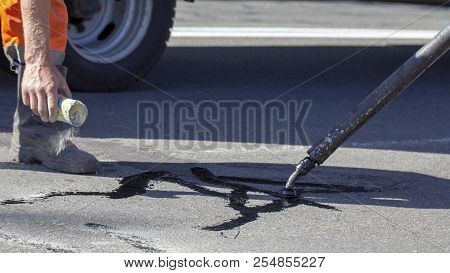 Workers Repair The Road, Pour Small Cracks With Bitumen To Prevent Further Destruction Of The Road S
