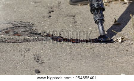 Workers Repair The Road, Pour Small Cracks With Bitumen To Prevent Further Destruction Of The Road S