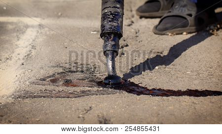 Workers Repair The Road, Pour Small Cracks With Bitumen To Prevent Further Destruction Of The Road S