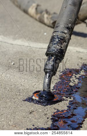 Workers Repair The Road, Pour Small Cracks With Bitumen To Prevent Further Destruction Of The Road S
