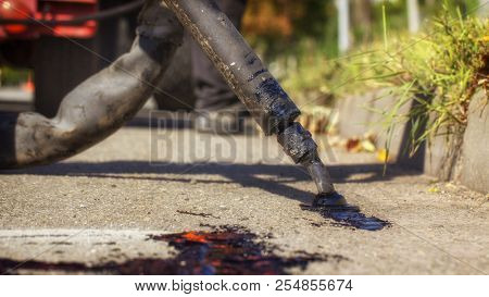Workers Repair The Road, Pour Small Cracks With Bitumen To Prevent Further Destruction Of The Road S