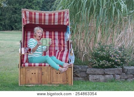 Wide-eyed And Terrified, The Woman On The Tablet Reads The Junk-e-mail