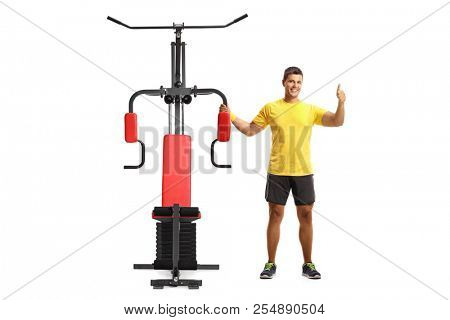 Young man with an exercising machine showing tumbs up isolated on white background