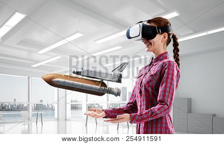 Young Caucasian Woman In Modern Office Interior Trying Virtual Reality Helmet And Viewing Space Shut