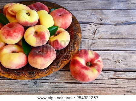 Fresh Organic Chinese Flat Peaches With Leaves On A Copper Plate On Old Wooden Rustic Table.saturn D