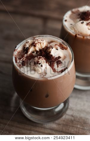 Latte Macchiato In A Glass With Cream On Wooden Background, Decorated Withcocoa Powder And Cinnamon,