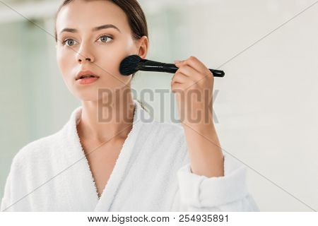 Beautiful Girl In Bathrobe Applying Bronzer With Brush