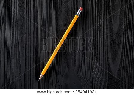 the yellow pencil isolated on a black wooden background